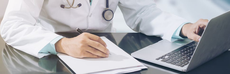 Médico faz anotações enquanto olha o faturamento de convênios para clínicas e consultórios no notebook