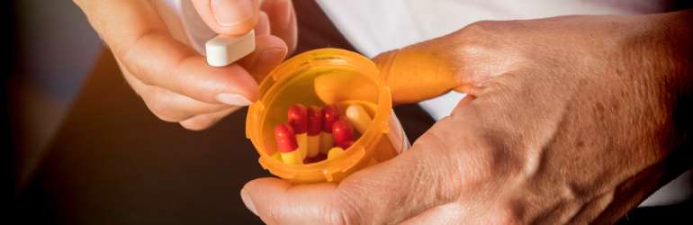 mãos seguram pílula e frasco de pílula com risco de administração indevida devido à letra ilegível de médicos