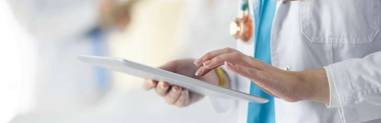 foco nas mãos de uma médica tocando um tablet - ferramenta para melhorar comunicação interna na clínica