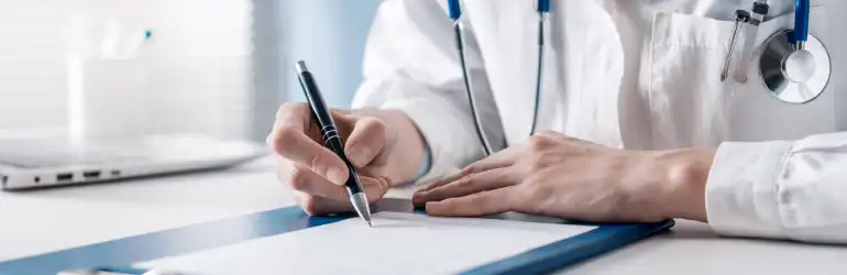 Médico escrevendo em um bloco de notas, usando caneta, com estetoscópio ao redor do pescoço, mostrando profissionalismo e atenção aos detalhes na saúde.