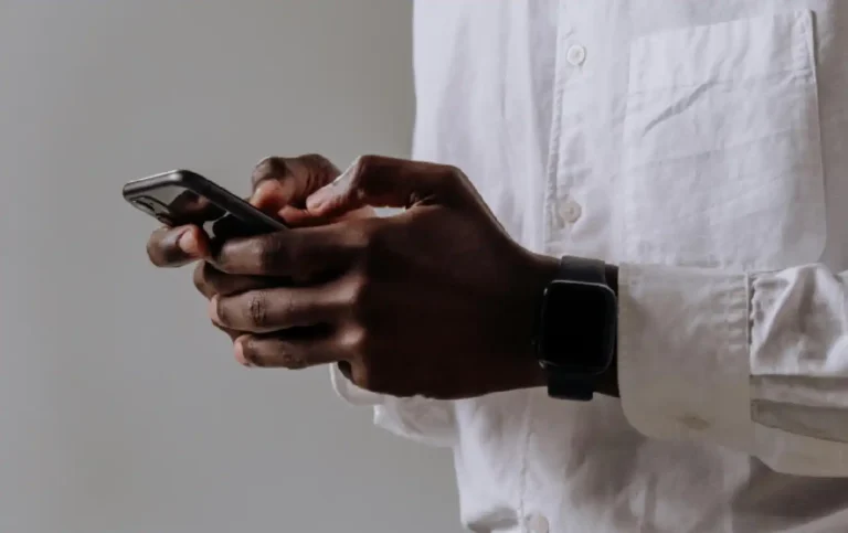 Homem usando smartphone em um ambiente moderno, enfatizando a conexão digital e a tecnologia no dia a dia.