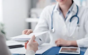 Profissional de saúde entregando prescrição com cálculo de medicamento a paciente em ambiente de clínica ou consultório.