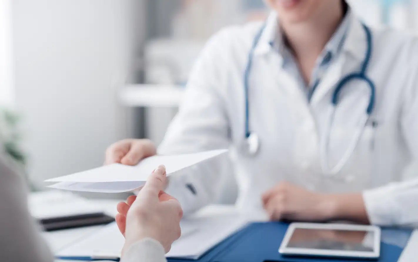 Profissional de saúde entregando prescrição com cálculo de medicamento a paciente em ambiente de clínica ou consultório.